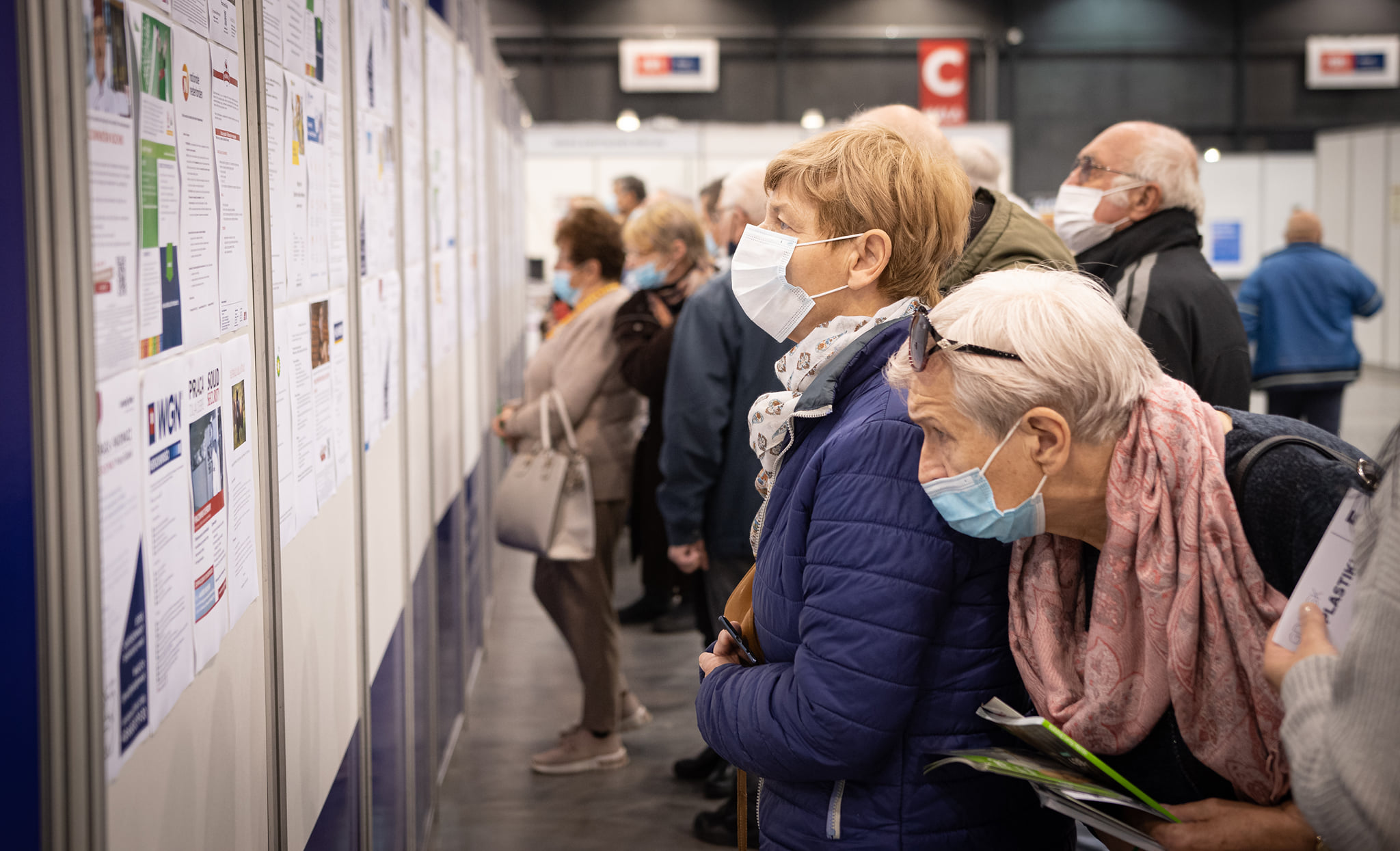 Na zdj. seniorzy czytają oferty pracy wywieszone na Job Wall-u